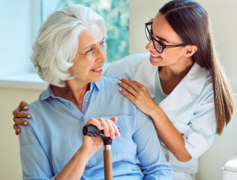 female caregiver and senior woman are smiling to each other