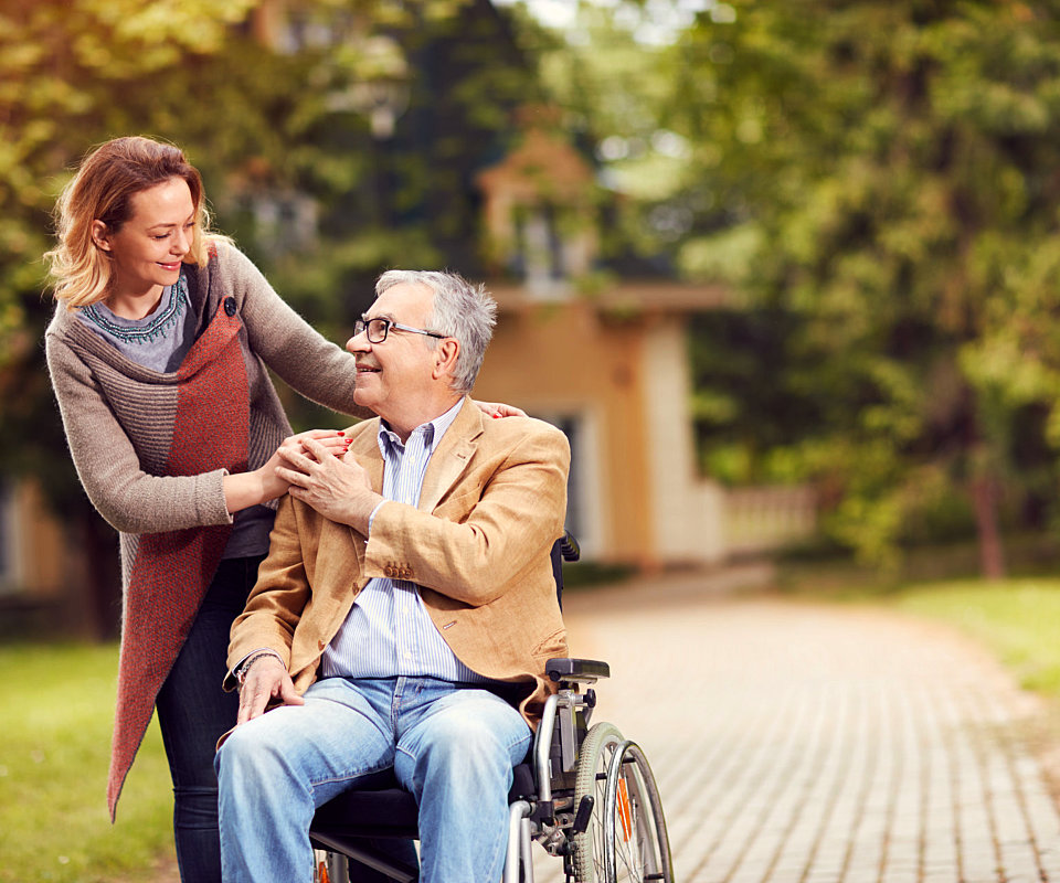 caregiver and senior man are smiling to each other at the park