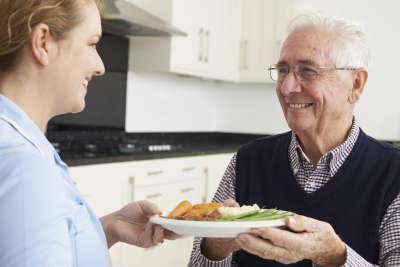 caregiver serving a meal to the senior man